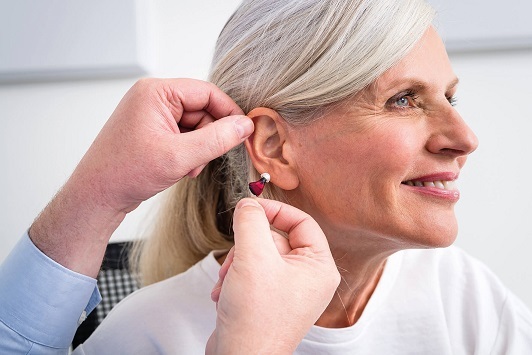 Ältere Frau bekommt von einem Hörgeräteakustiker ein modernes Hörgerät angepasst.